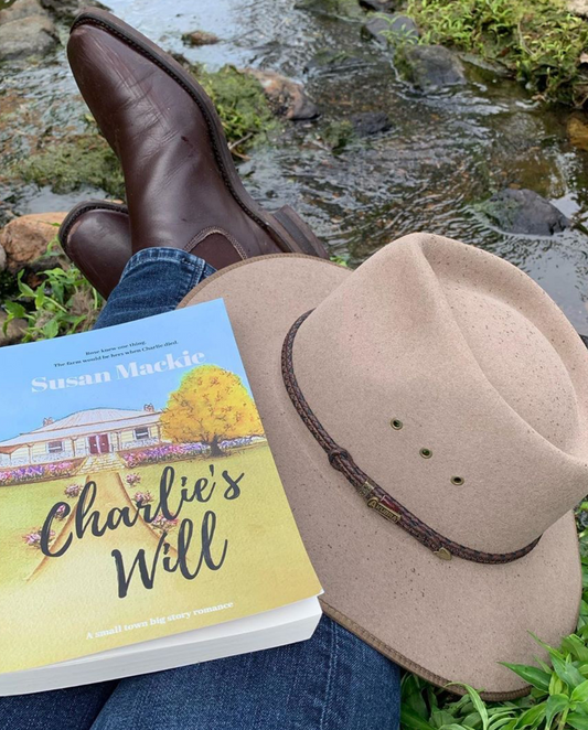 Cowboy boots and hat and a copy of Charlie's Will by Susan Mackie.