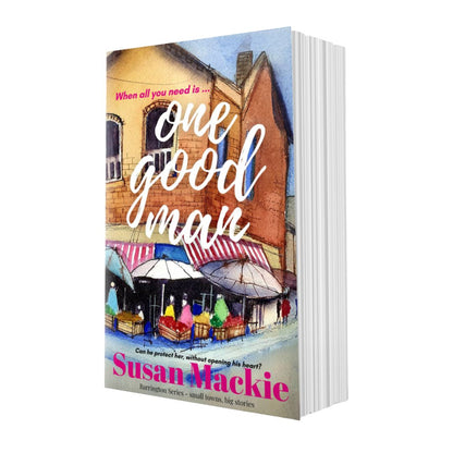 Book titled 'One Good Man' by Susan Mackie with a colorful street scene on the cover.